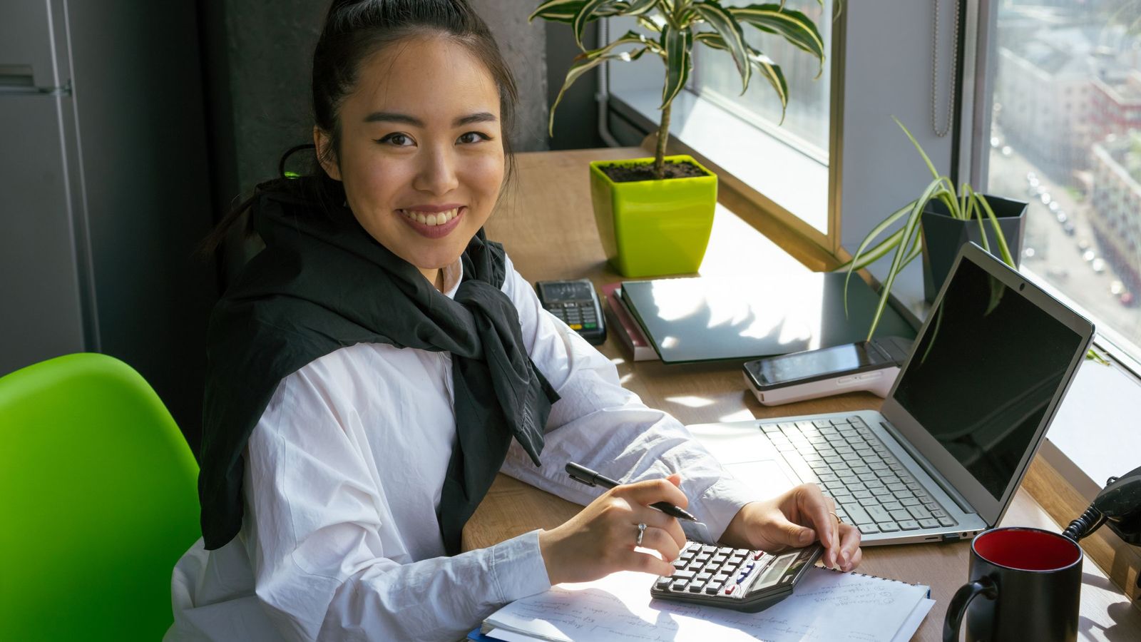 เจ้าของร้านยิ้มพลางกดเครื่องคิดเลขที่โต๊ะทำงานริมหน้าต่างที่มีแสงแดดส่องเข้ามา มีเอกสารและโน้ตบุ๊กวางอยู่บนโต๊ะ